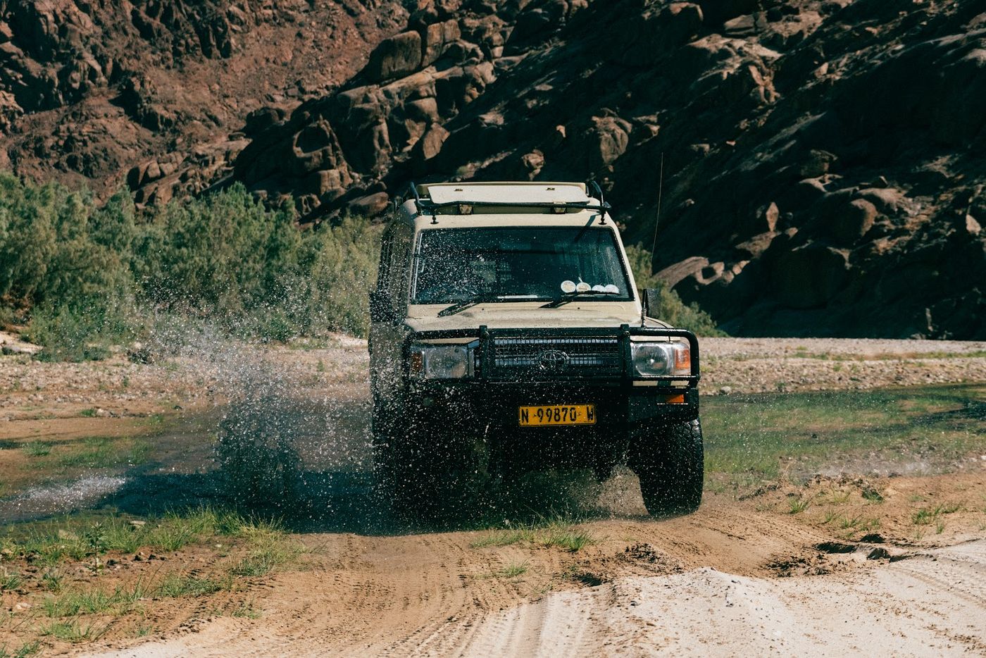 Safari 4x4 splashing through a river crossing in a rocky valley
